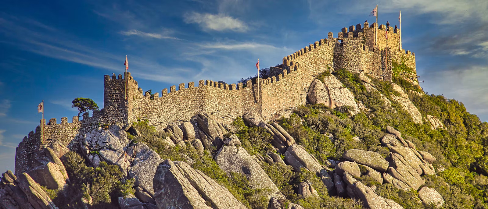 The walls of the Moorish Castle running along the ridge above Sintra, with forest falling away below