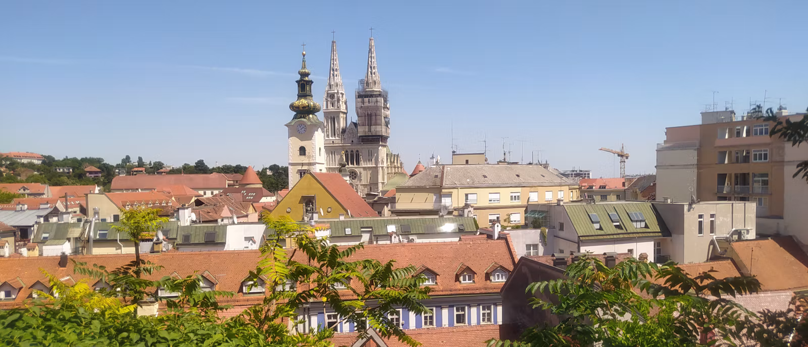 The twin spires of Zagreb Cathedral above the roofs of the city, seen across the treetops