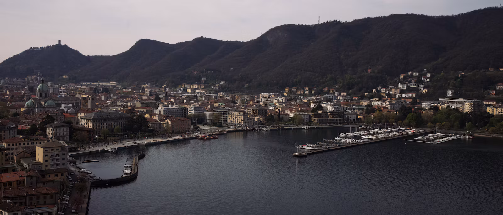 Como's lakefront, harbour and cathedral dome below the hills, at dusk